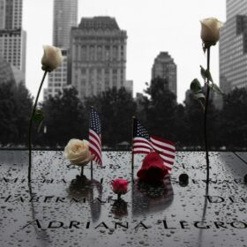 American flags and white roses placed on the engraved names at the National September 11 Memorial in remembrance